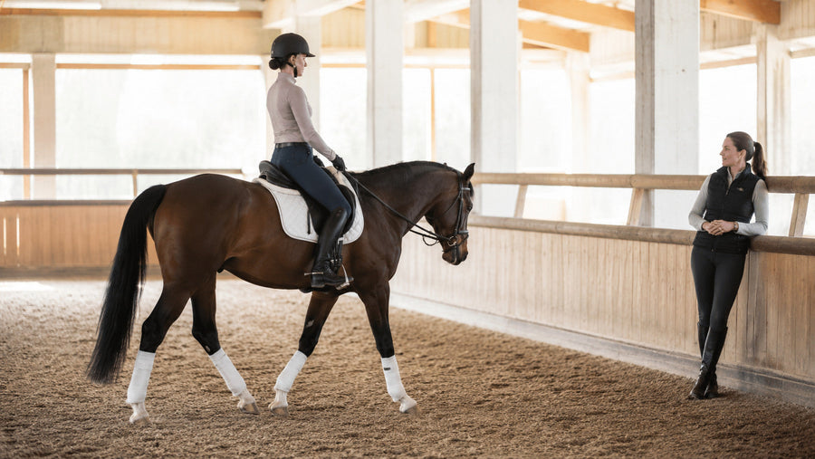 Adult rider taking a supervised riding lesson in an indoor arena