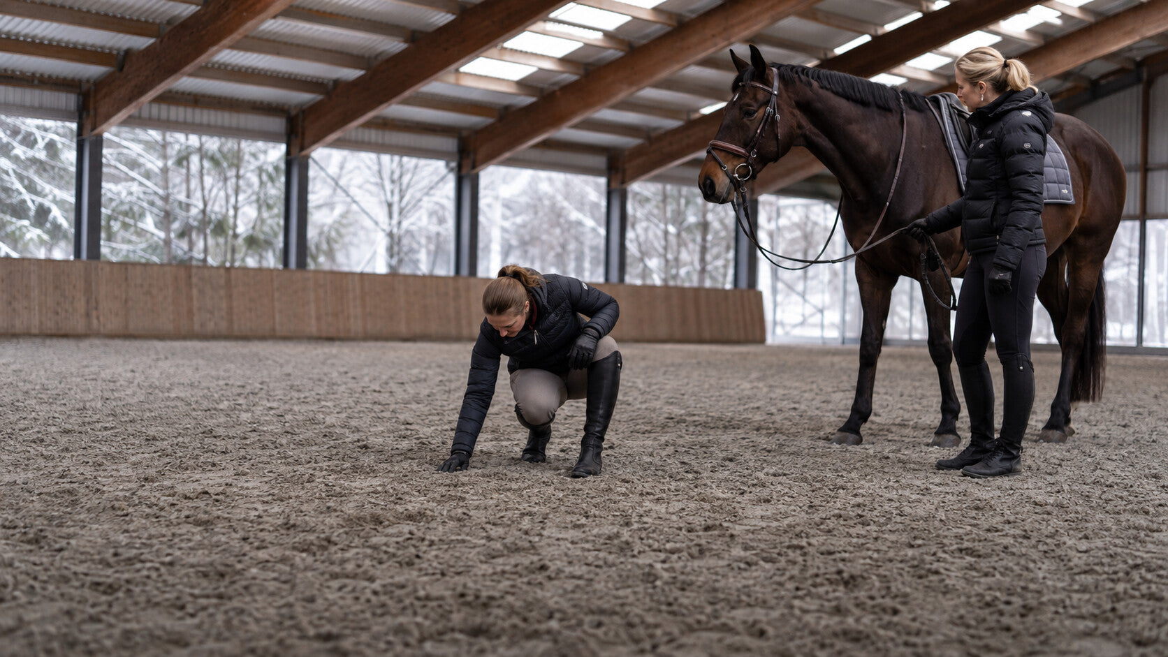 Rider inspecting winter arena footing before work